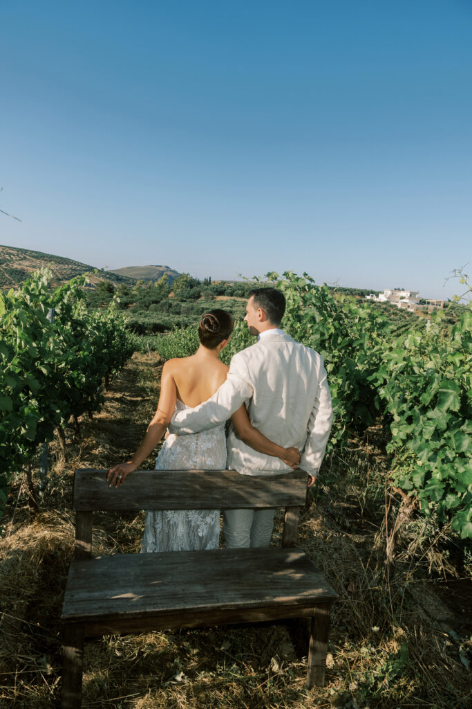 Wedding at Scalarea Estate Crete- Couple just married embracing and walking amongst beautiful green vineyard