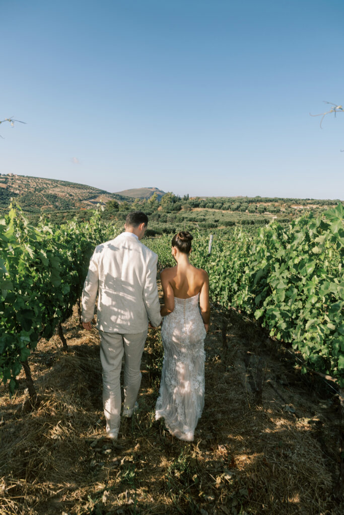 Wedding At Scalarea Estate - Bride and Groom walking amongst the lush green vineyard