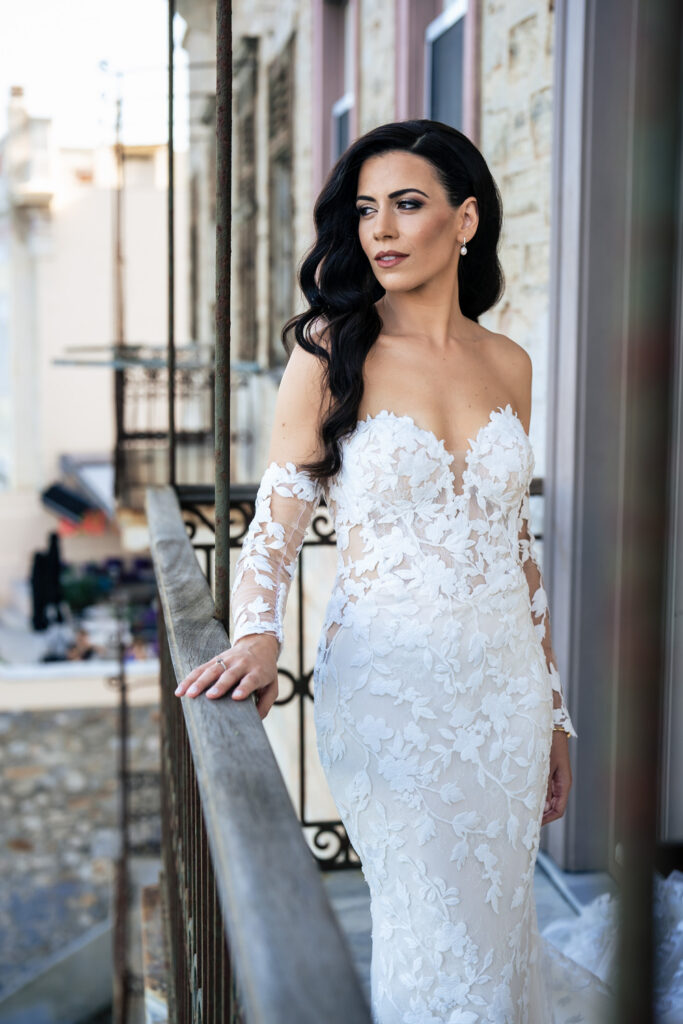 A romantic wedding in Syros - Ilia & Flavio - Ilia on balcony in wedding dress